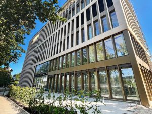 Modernes Bürogebäude mit Glasfronten und Bäumen.